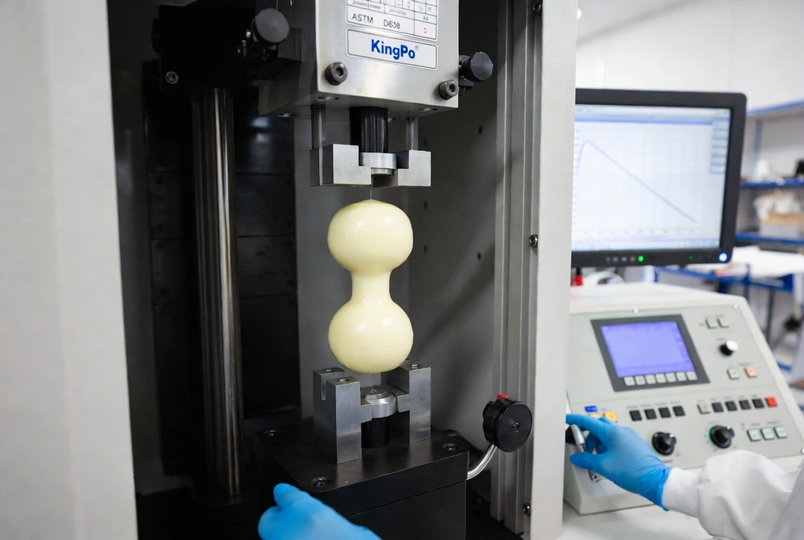 KingPo tensile strength testing machine during active ASTM D638 tensile test with specimen clamped in grips.