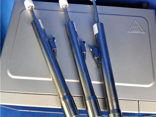 Set of three stainless-steel UL 923 microwave oven door force test devices arranged on a laboratory case.