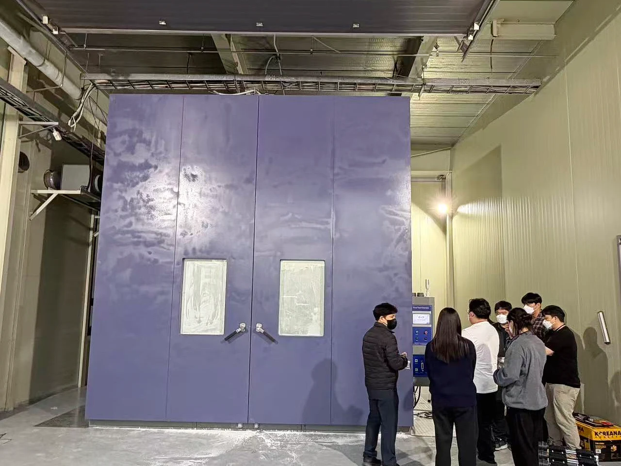 KINGPO KP-DC4000 64 m³ walk-in sand and dust test chamber installed at SGS Korea with project personnel beside the control system.